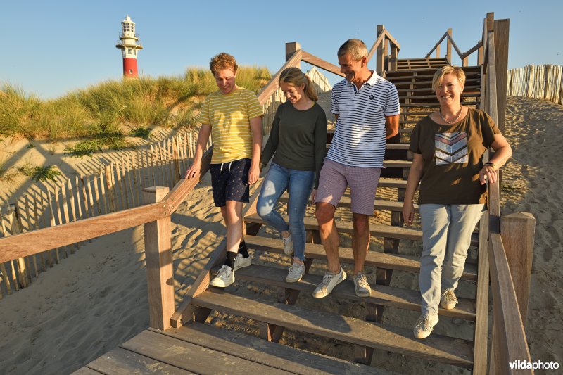 Wandelaars nemen de houten loopbrug aan de IJzermonding